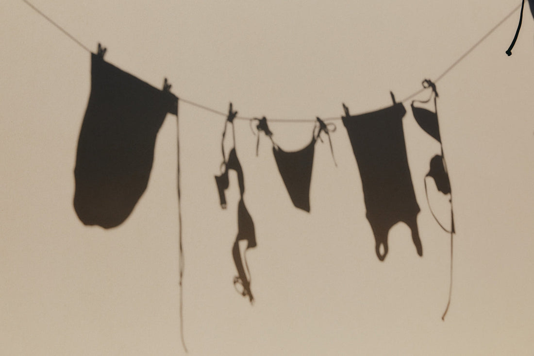 Shadows of clothes on a washing line cast against a pale wall.