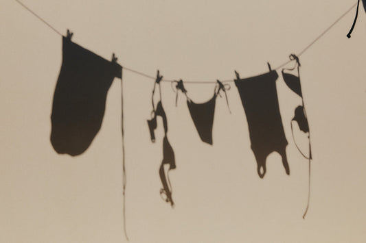 Shadows of clothes on a washing line cast against a pale wall.
