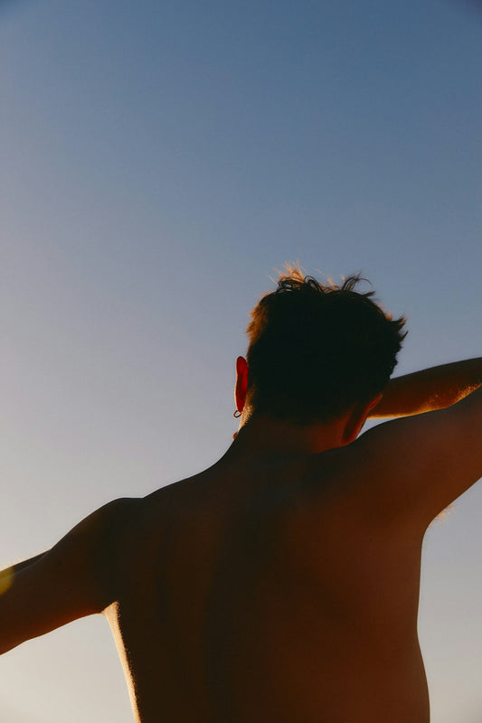 Back view of a man outdoors at sunset, highlighting the importance of daily mineral sunscreen for full-body sun protection.