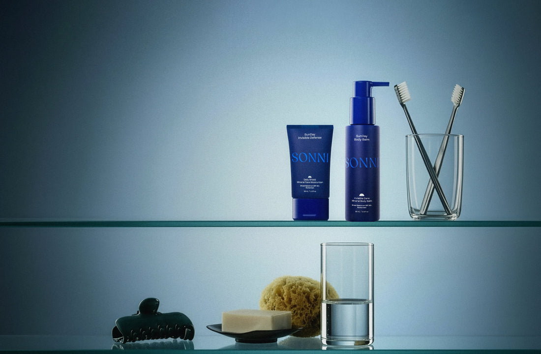 SONNI suncare products displayed on a glass shelf, including a blue tube and pump bottle, styled with minimal everyday objects against a soft blue background.